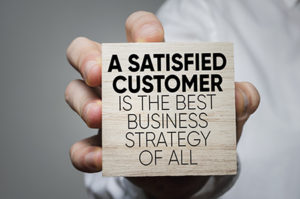 NJ ITM vendors, block with words " A satisfied customer is the best business strategy of all" being held in a hand