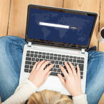 Person sitting on the floor with a laptop in lap using a search engine depicting how important Ocean County web design is